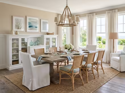 AI-generated coastal dining room interior design: a white slipcovered sofa with sea-glass blue and striped cushions