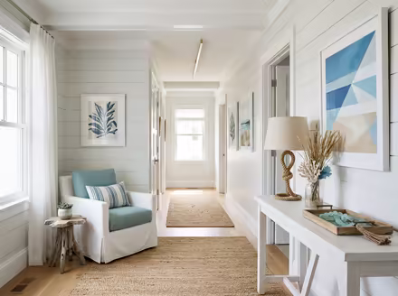 AI-generated coastal hallway interior design: a white slipcovered sofa with sea-glass blue and striped cushions