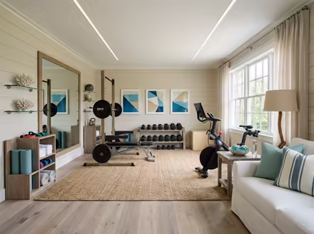 AI-generated coastal home gym interior design: a white slipcovered sofa with sea-glass blue and striped cushions