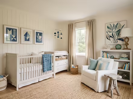 AI-generated coastal nursery interior design: a white slipcovered sofa with sea-glass blue and striped cushions